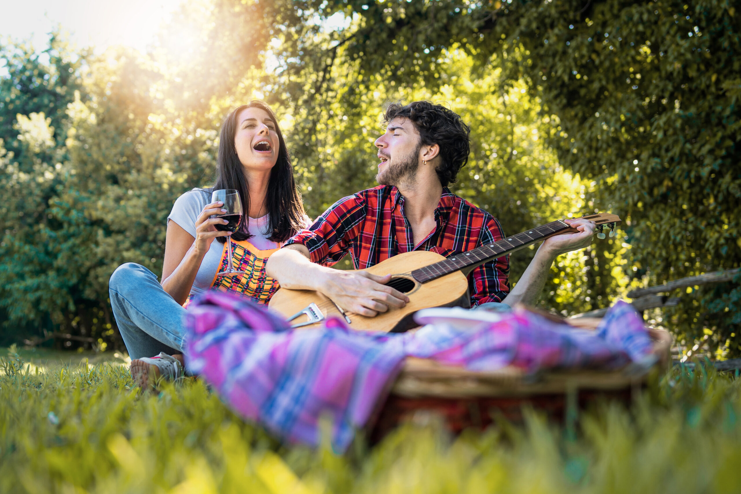 Pareja joven canta en un picnic en un espacio público